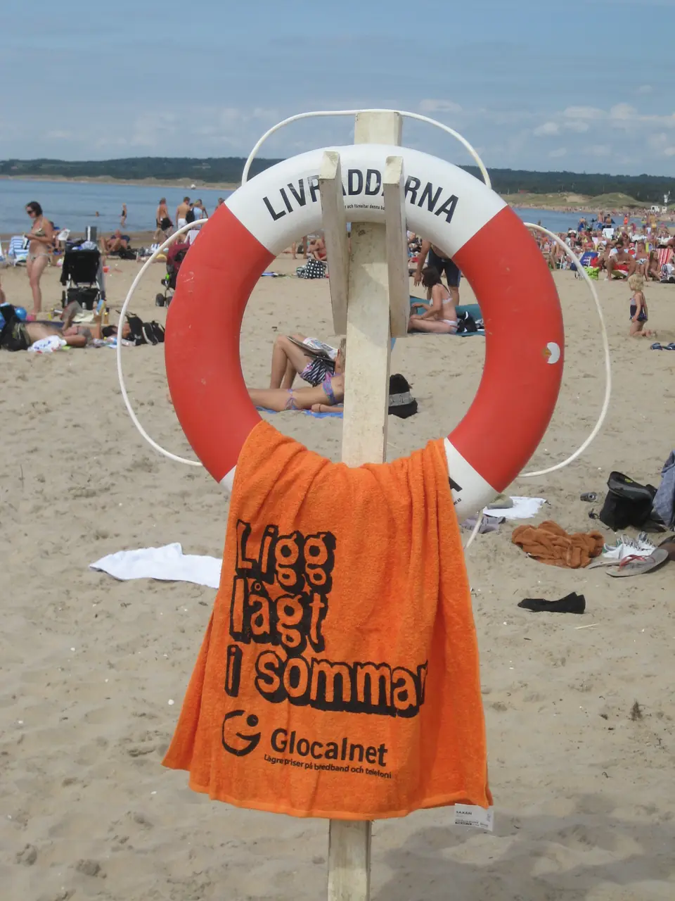 Beach towel with the text Ligg lågt i sommar on a beach