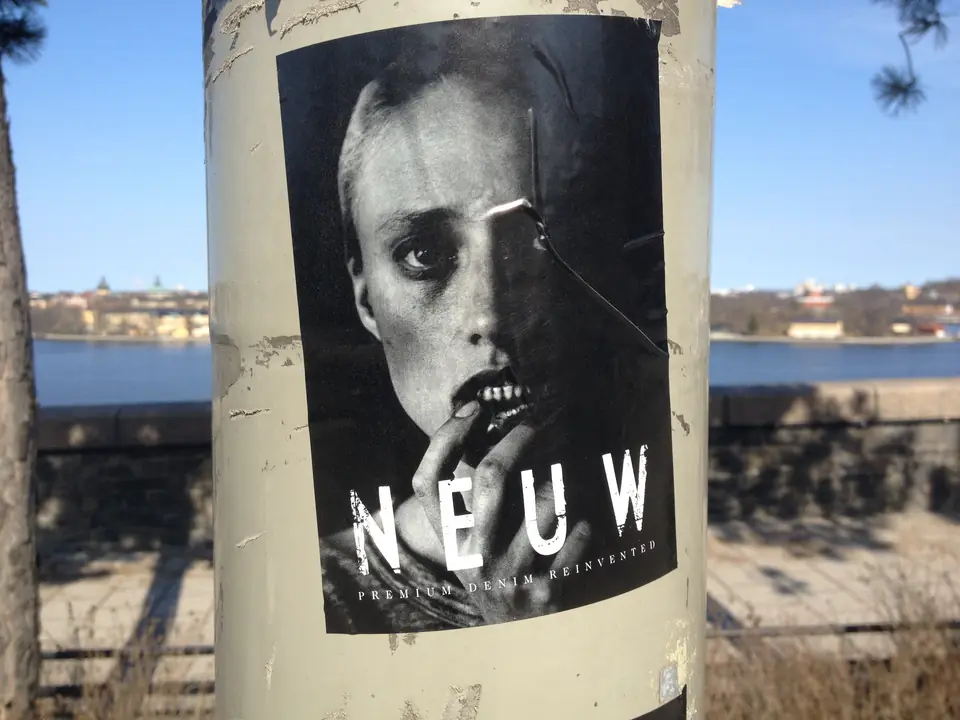 Neuw Denim-plakat på en lygtepæl ved vandet