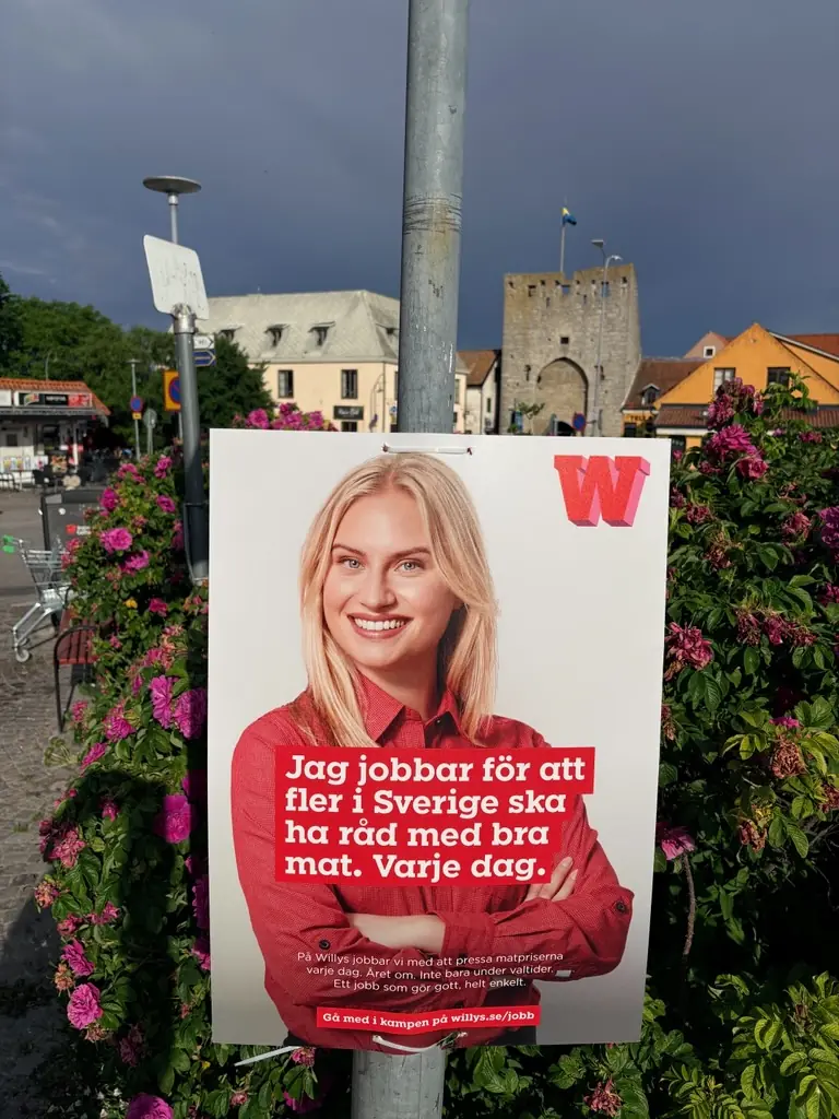 Willys-affisch på en stolpe framför ringmuren i Visby